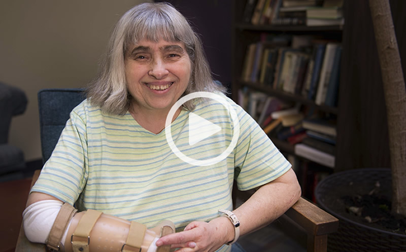 A photo of Margaret smiling with a playbutton layered overtop.