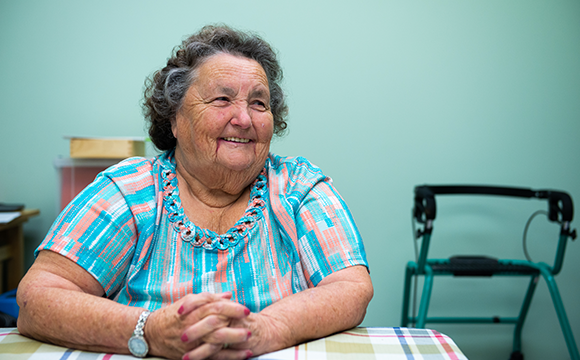 Alice sitting with her hands crossed and smiling off camera