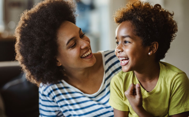 A mom laughing with her son sitting on a couch.