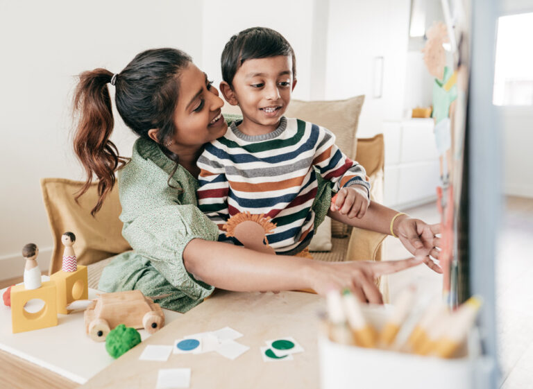 A photo of a child doing some painting with their Mom at home.