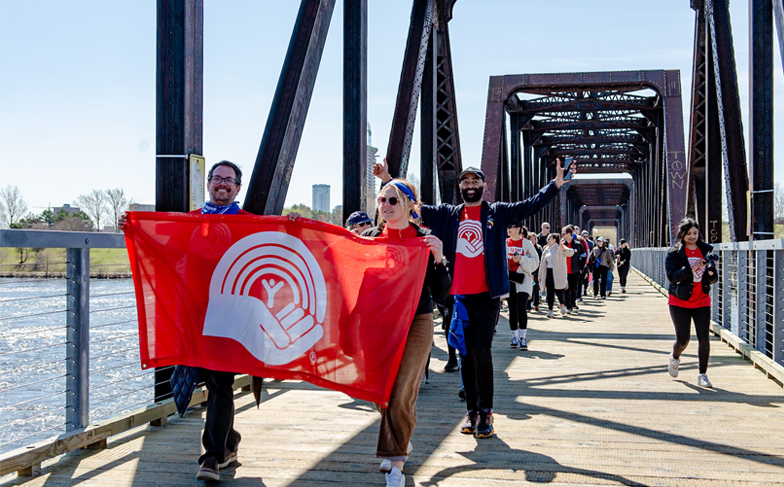 Move for Youth participants walking over a bridge holding a United Way flag.