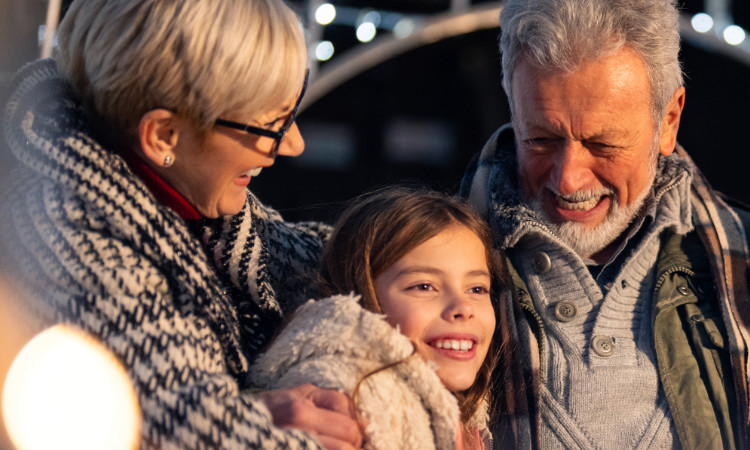 A photo of grandparents holding their grandkids surrounded by holiday lights.