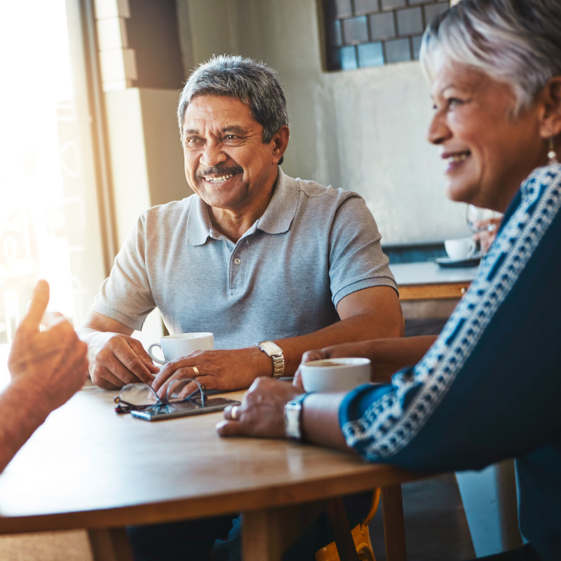 A photo of a senior couple having a conversation with friends around the dinner table.