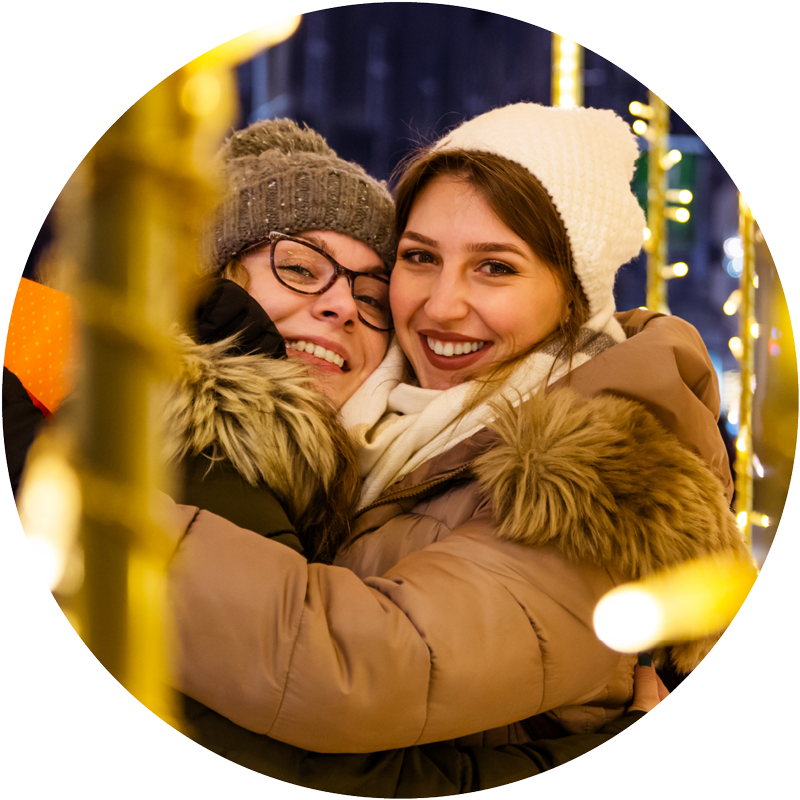 Two friends outside under the holiday lights.
