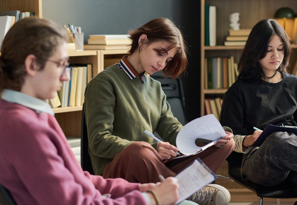 A photo of a youth working on a project with a small group of people.