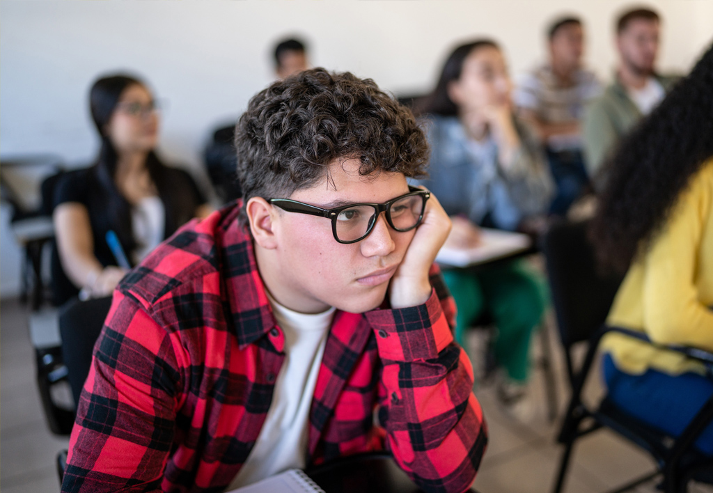 A photo of a youth working on some school work in a classwroom.