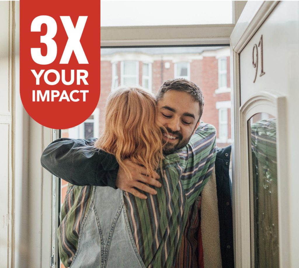 Two people hugging at a front door of a home.